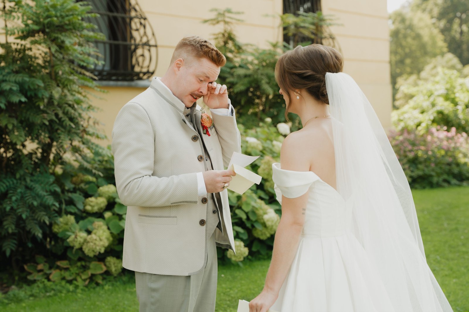 Bräutigam mit Freudentränen beim First Look, Braut mit Schleier im Garten des Palais Schönburg